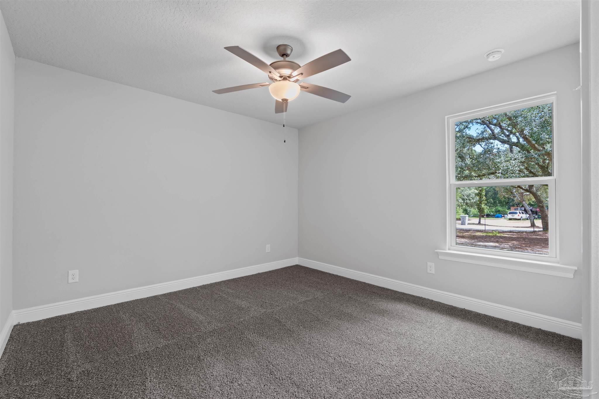 4289 Carl Booker Road Milton, FL 32583 - Photo 32 of 40 an empty room with wooden floor fan and windows
