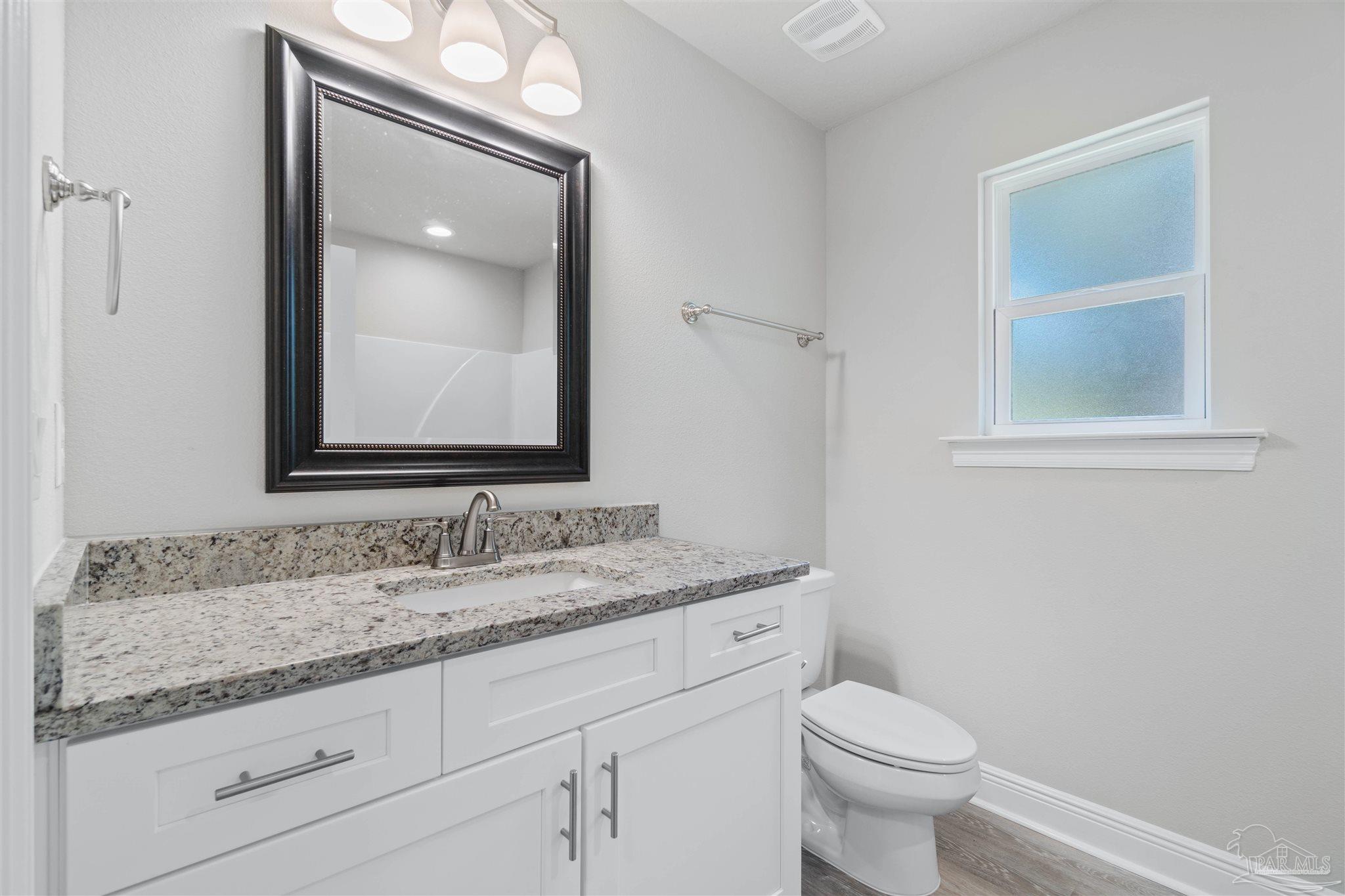 4289 Carl Booker Road Milton, FL 32583 - Photo 34 of 40 a bathroom with a granite countertop toilet sink and mirror