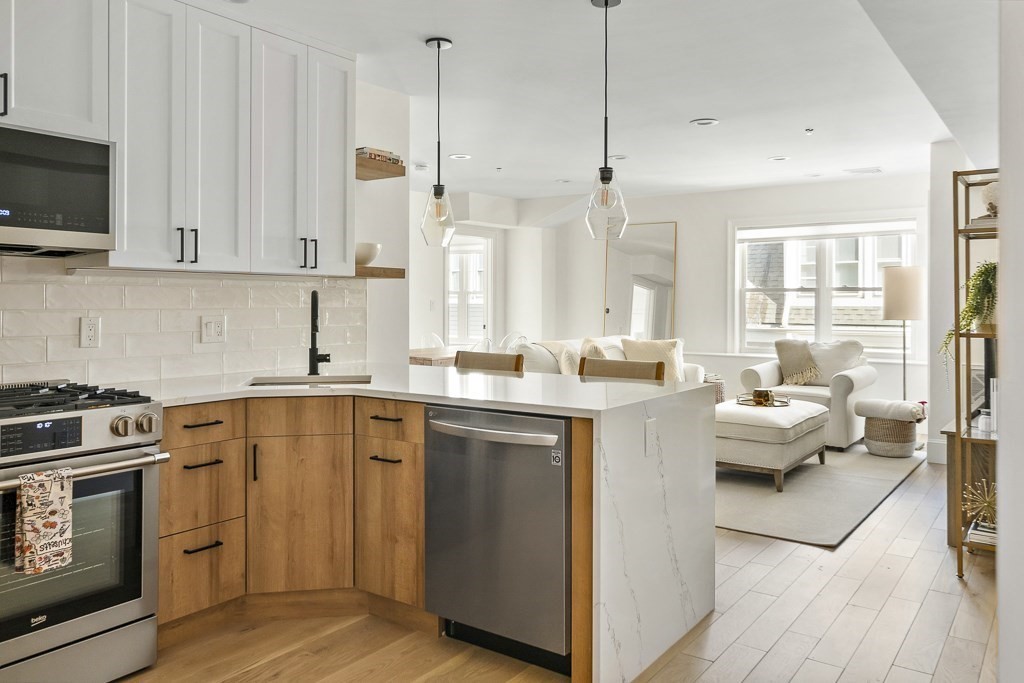 a kitchen with a stove a sink and white cabinets with wooden floor