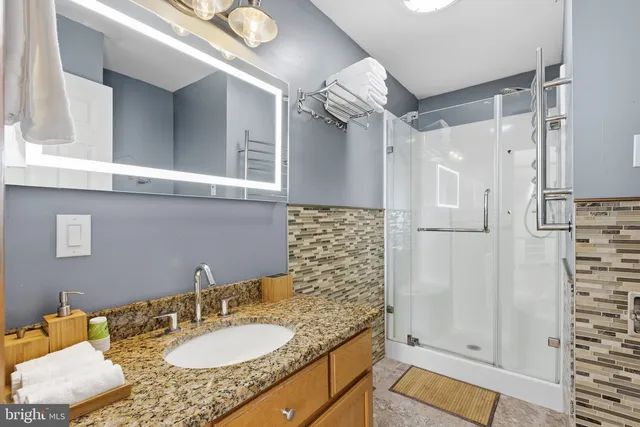 a bathroom with a granite countertop sink a mirror and shower