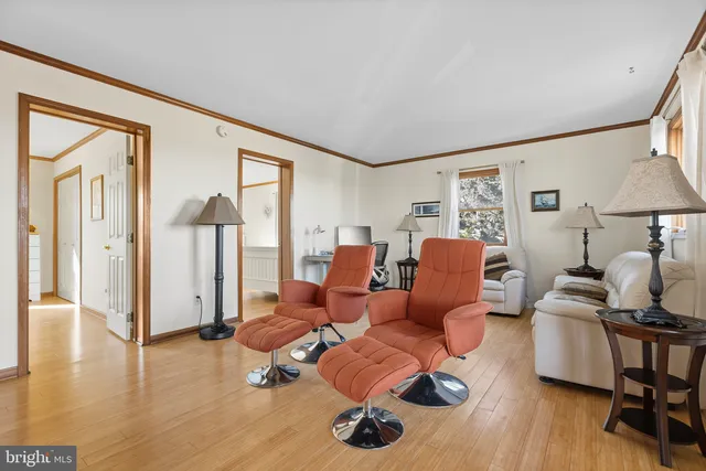 a living room with furniture hard wood floor and a floor to ceiling window
