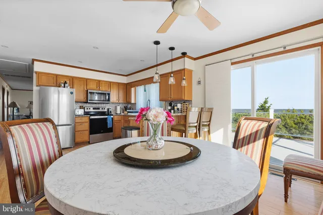 a dining room with furniture a kitchen view and large windows