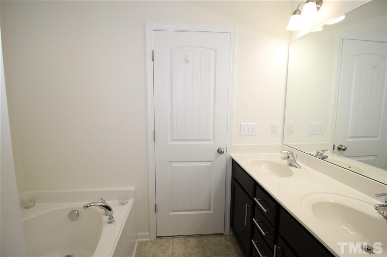 1045 Grand Ridge Drive Rolesville, NC 27571 - Photo 15 of 23 a bathroom with a double vanity sink a mirror and a bathtub