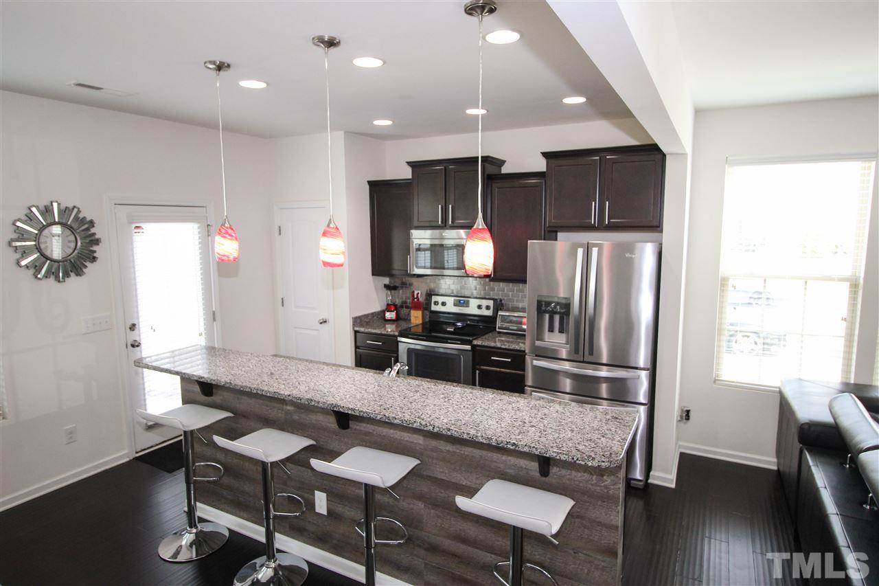 1045 Grand Ridge Drive Rolesville, NC 27571 - Photo 7 of 23 a kitchen with refrigerator cabinets dining table and chairs