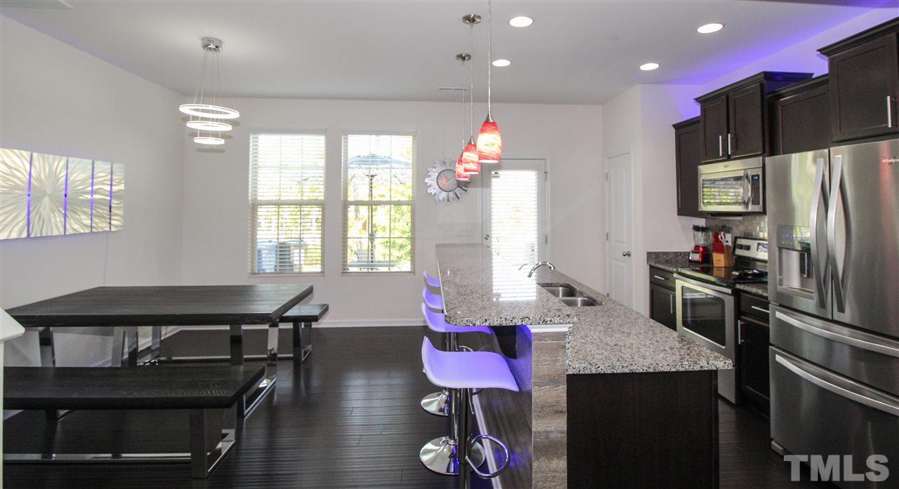 1045 Grand Ridge Drive Rolesville, NC 27571 - Photo 8 of 23 a kitchen with a table chairs refrigerator and microwave