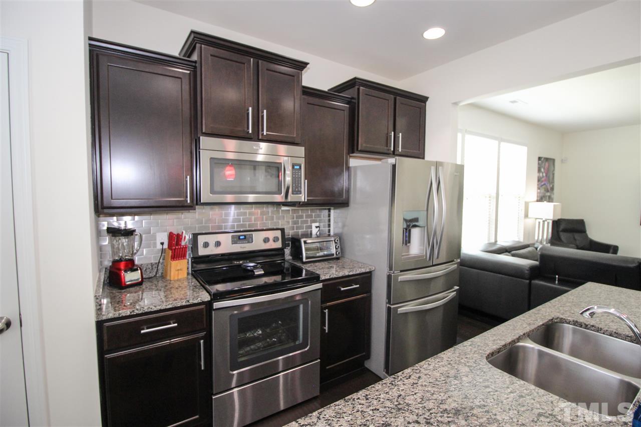 1045 Grand Ridge Drive Rolesville, NC 27571 - Photo 10 of 23 a kitchen with stainless steel appliances granite countertop a refrigerator a stove and a sink with wooden floor