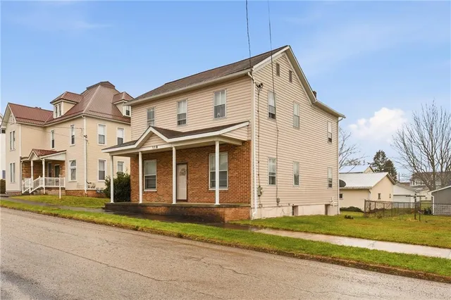 a view of a white house with a yard and table and chairs next to door