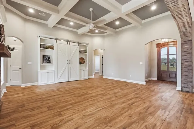 a view of an empty room with window and wooden floor