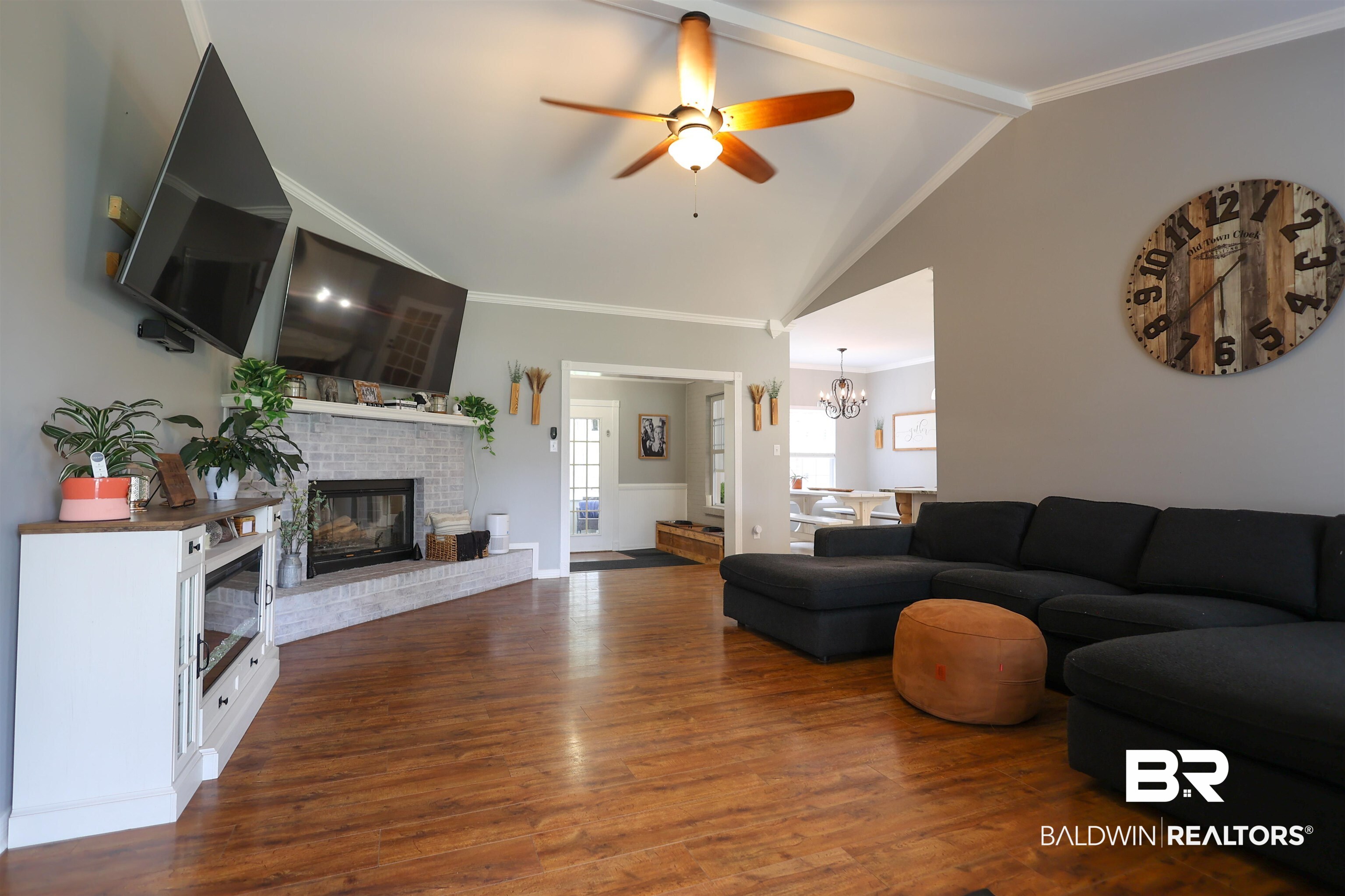 5151 Beatrice Road Gulf Shores, AL 36542 - Photo 10 of 50 Living area with ornamental molding, dark wood-style floors, lofted ceiling with beams, a fireplace, and hanging lights