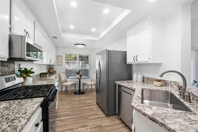 a kitchen with a refrigerator a stove a sink dishwasher and wooden cabinets with wooden floor