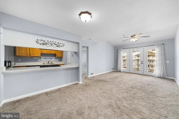 a view of an empty room with a window and a kitchen