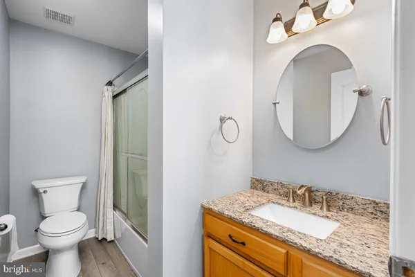 a bathroom with a granite countertop sink mirror vanity and toilet
