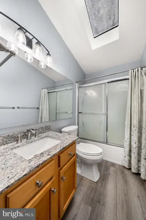 a bathroom with a granite countertop toilet sink and mirror