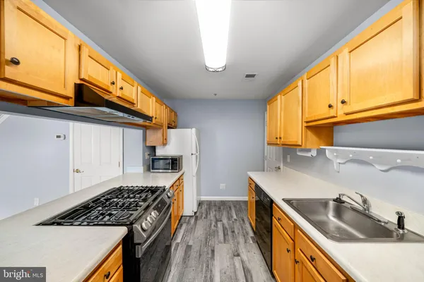 a kitchen with stainless steel appliances granite countertop a sink a stove and a wooden cabinets