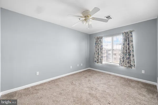 an empty room with chandelier fan and windows