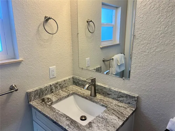 a bathroom with a granite countertop sink a mirror and shower