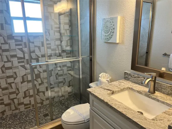 a bathroom with a granite countertop sink a toilet and shower