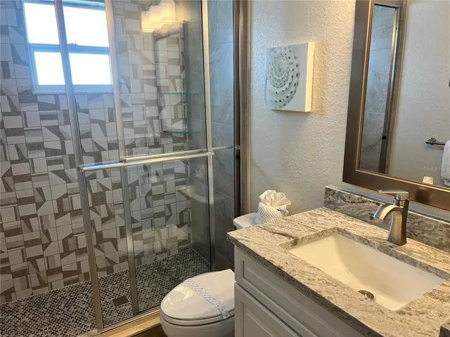 a bathroom with a granite countertop sink a toilet and shower