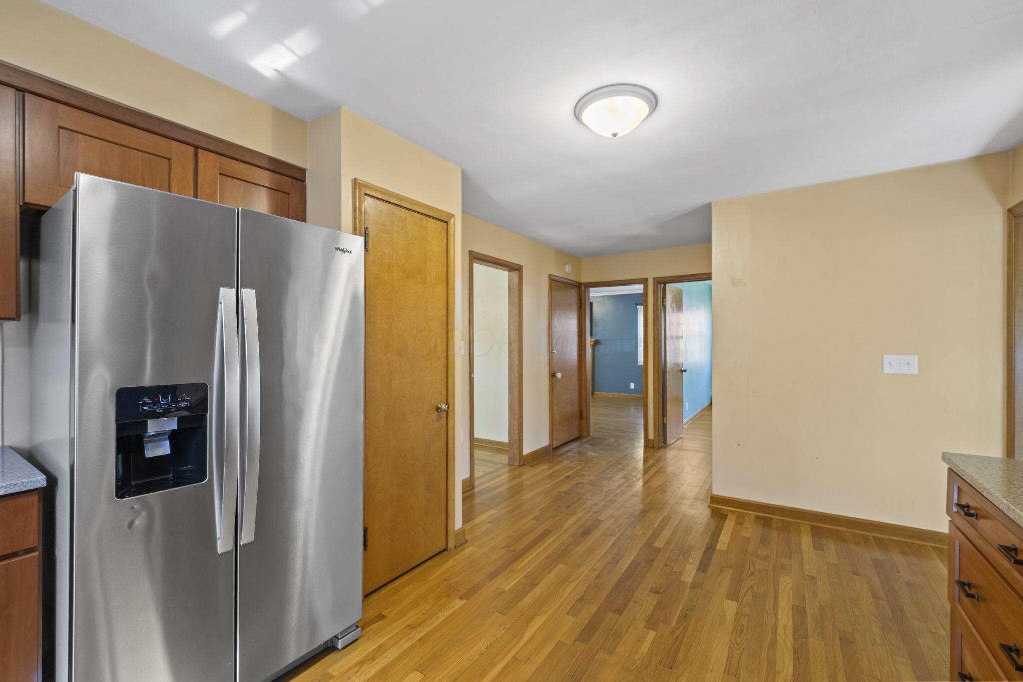 40 South Kellner Road Columbus, OH 43209 - Photo 5 of 57 Stainless steel side-by-side refrigerator, wood-finish flooring, wood-finish cabinetry, and neutral wall paint