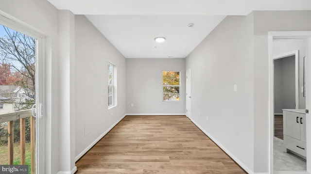 a view of a hallway with wooden floor and a living room
