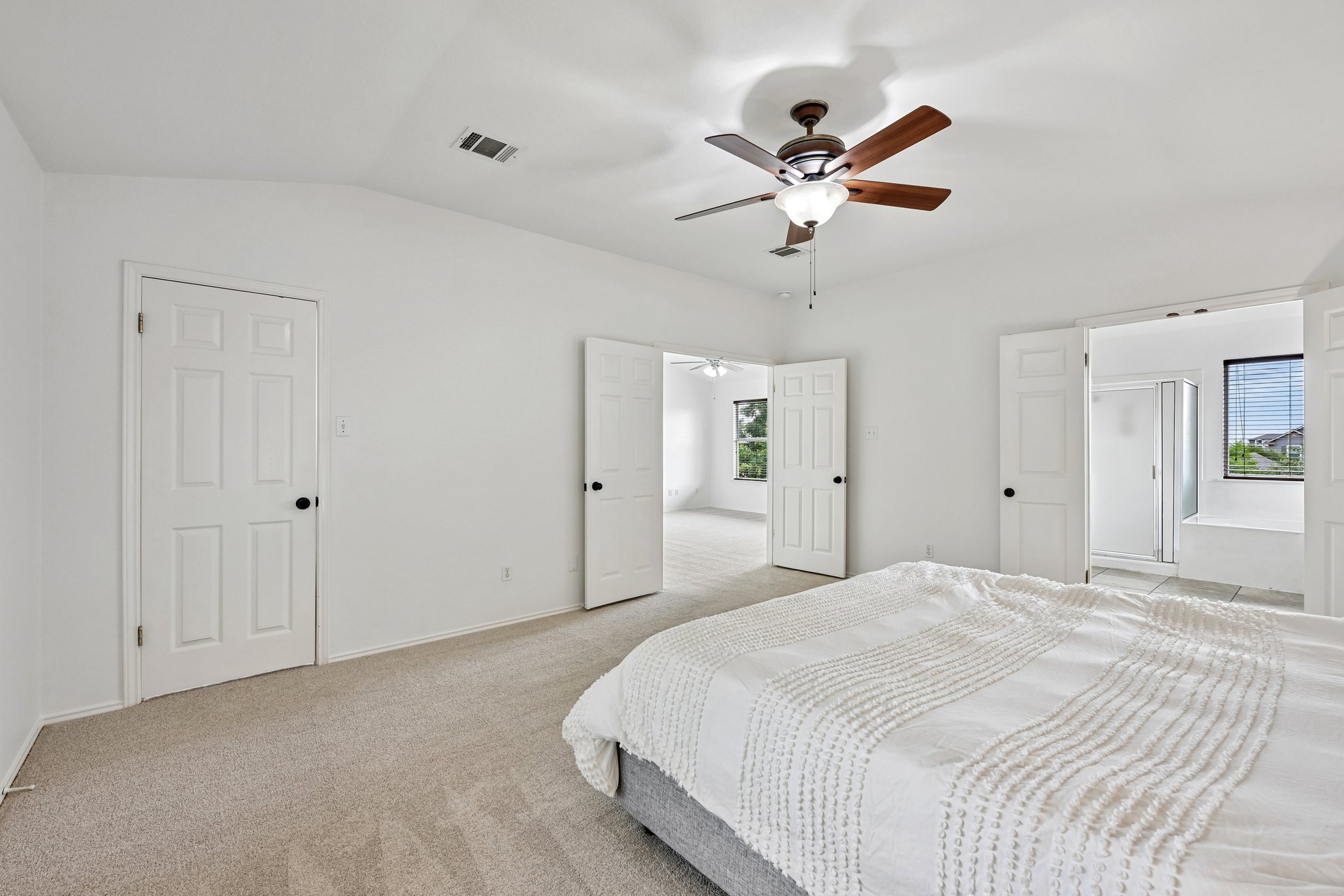4100 Mocha Trail Austin, TX 78728 - Photo 14 of 33 A well-lit primary bedroom offers plush carpet flooring, a ceiling fan for comfort, and convenient access to a private bathroom.