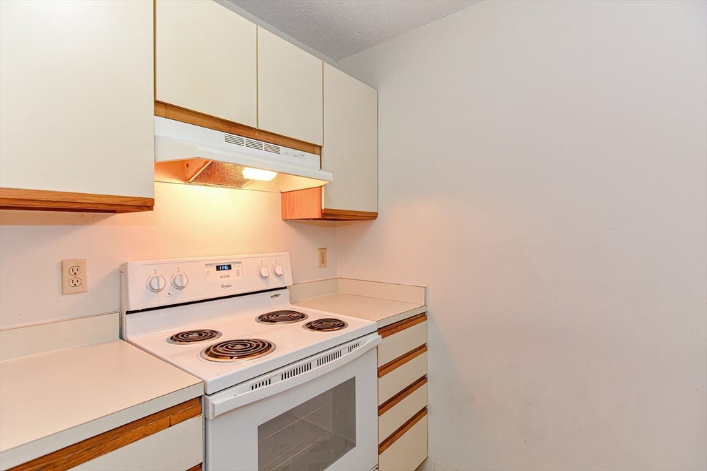1811 Franklin Crossing Road, Unit 1811 Franklin, MA 02038 - Photo 14 of 31 a kitchen with a stove and a white cabinets