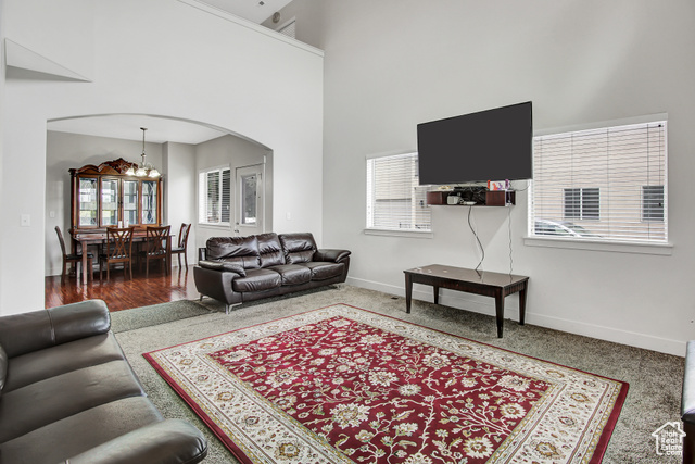4 Hanauer Place Murray, UT 84107 - Photo 5 of 24 Carpeted living room featuring arched walkways, a chandelier, and a high ceiling
