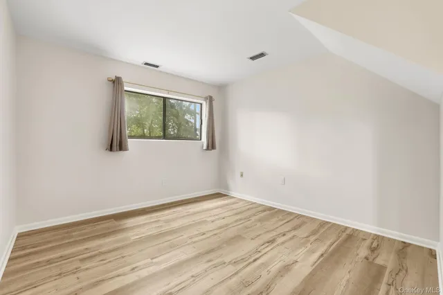 an empty room with wooden floor and window