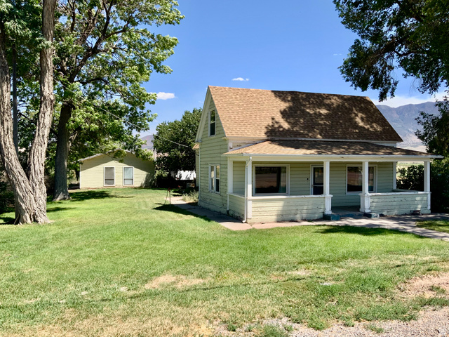 View of front of property featuring roof with shingles, a porch, and a front yard