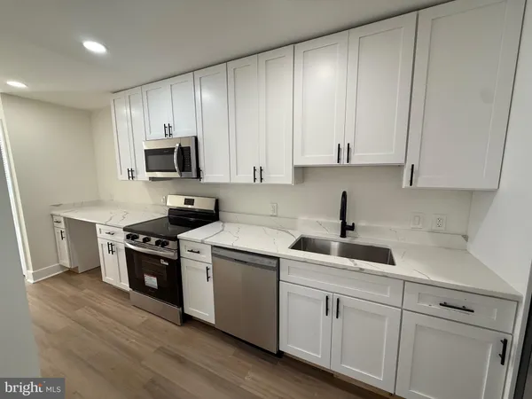 a kitchen with cabinets stainless steel appliances a sink and wooden floor