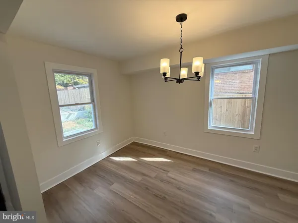 a view of a room with wooden floor chandelier and windows