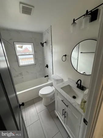 a bathroom with a sink a toilet a mirror and bathtub
