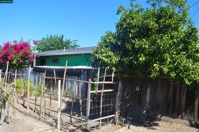 a view of a house with a wooden bench next to a yard