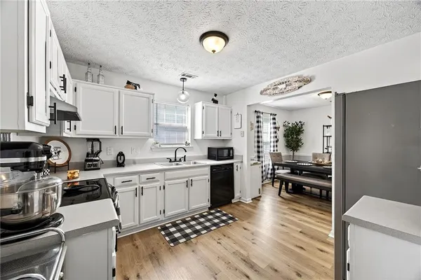 a kitchen with stainless steel appliances a stove a sink dishwasher and a refrigerator with wooden floor