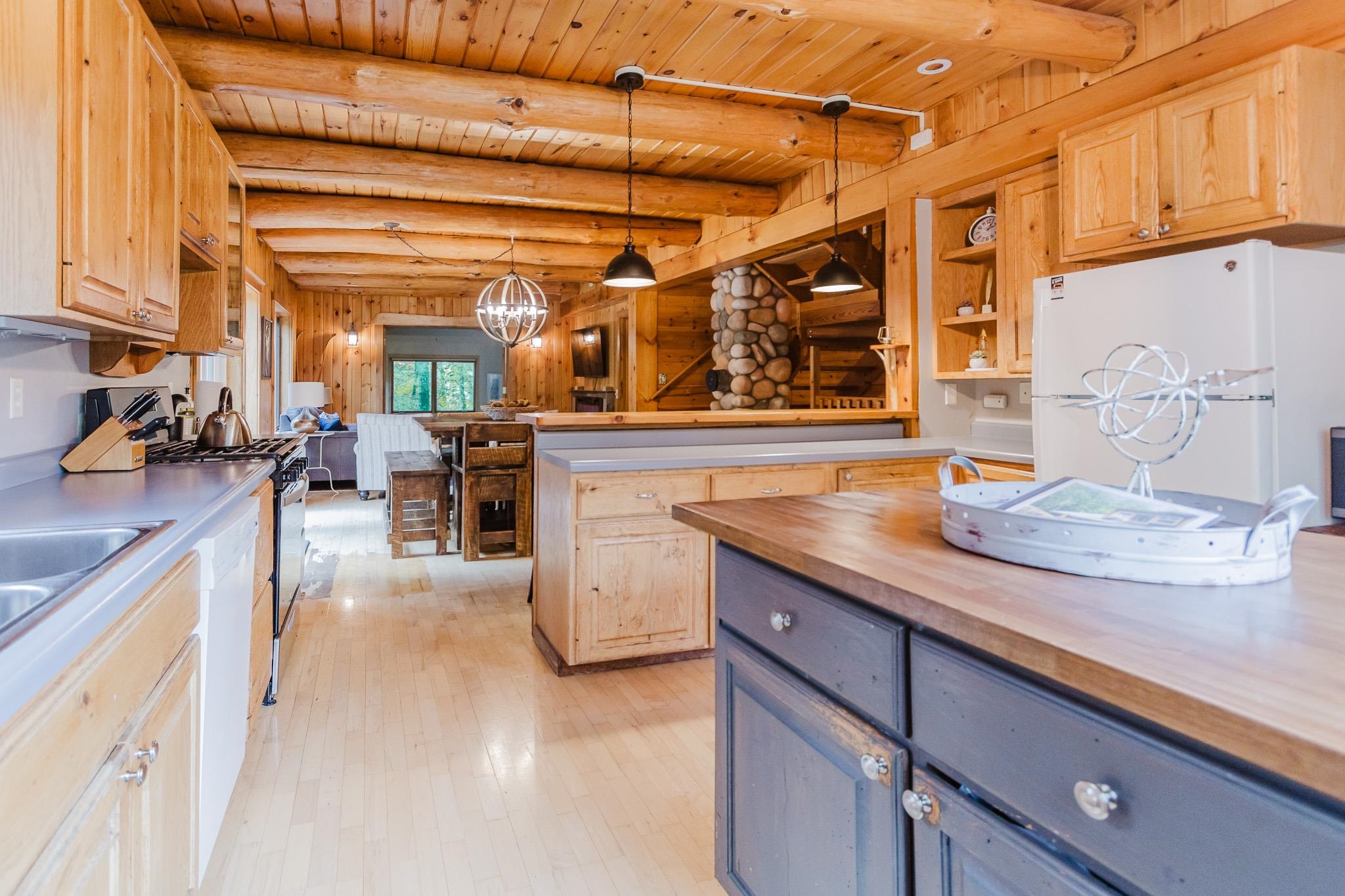 1690 Aho Road Duluth, MN 55804 - Photo 8 of 39 Kitchen with decorative light fixtures, white appliances, butcher block countertops, light brown cabinetry, and a wood ceiling with exposed beams