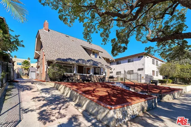 a front view of a house with yard tree and wooden fence