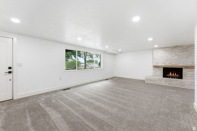 871 Bonita Way Centerville, UT 84014 - Photo 40 of 61 Spacious room featuring a stacked stone fireplace with a wood mantle, recessed lighting, expansive windows, and new carpeting