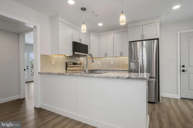 a kitchen with stainless steel appliances granite countertop a refrigerator a sink a stove a microwave and wooden floor