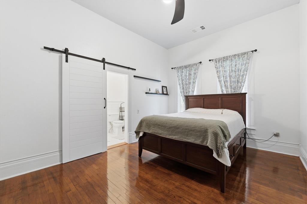 415 South Rice Street Hamilton, TX 76531 - Photo 10 of 28 Hardwood flooring featuring white walls, a barn-style sliding door, ceiling fan, and closet