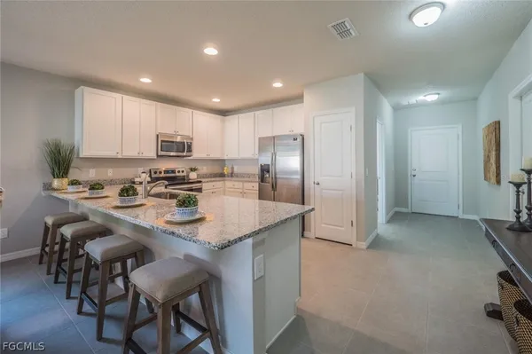a kitchen with stainless steel appliances granite countertop a refrigerator a stove a sink a dining table and chairs