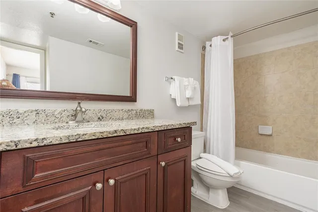 a bathroom with a granite countertop bathtub sink vanity mirror and toilet