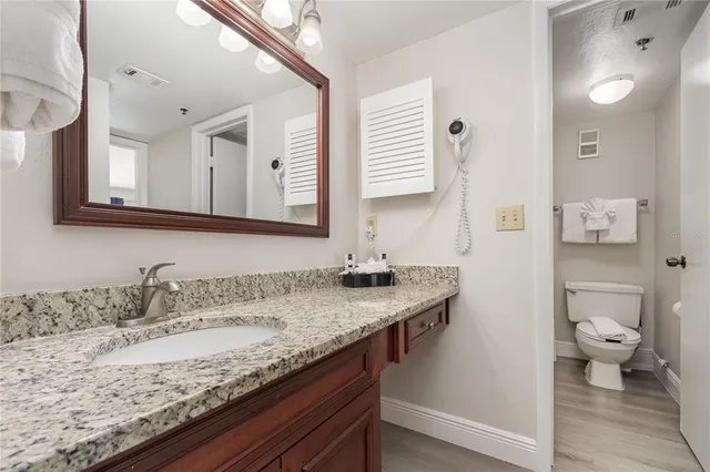 a bathroom with a granite countertop sink and a toilet