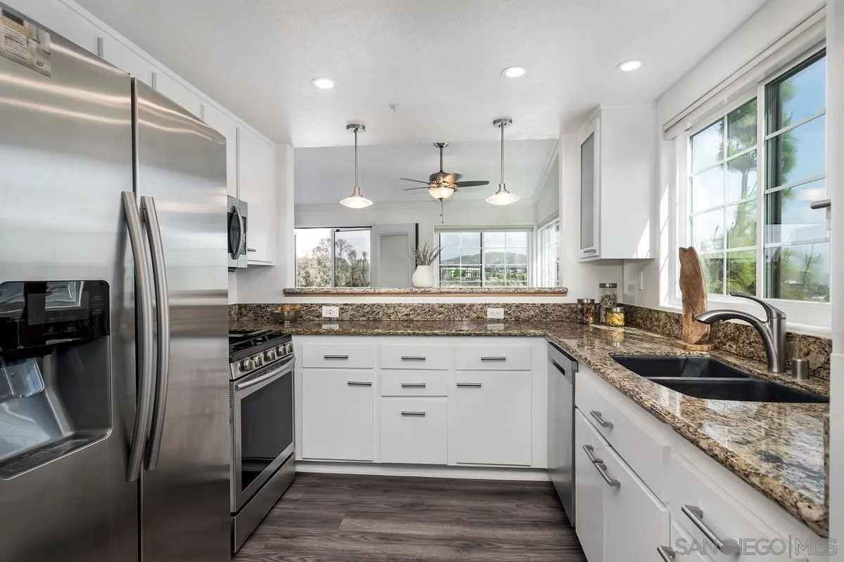 16470 Avenida Venusto, Unit F Rancho Bernardo, CA 92128 - Photo 13 of 30 a kitchen with granite countertop a sink stainless steel appliances and cabinets