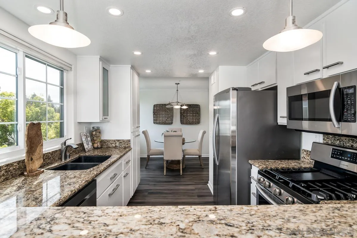 16470 Avenida Venusto, Unit F Rancho Bernardo, CA 92128 - Photo 10 of 30 a kitchen with stainless steel appliances kitchen island granite countertop a sink and a stove