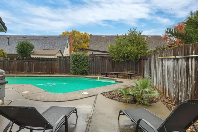 a view of a backyard with swimming pool and furniture