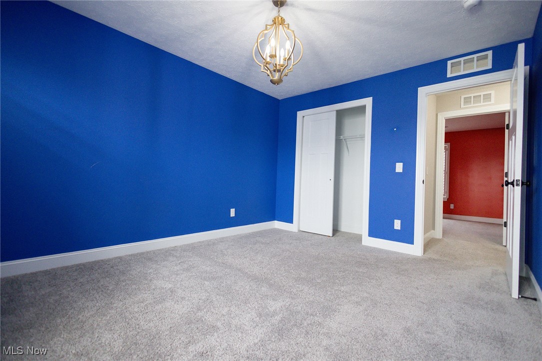 37328 Sandy Ridge Drive North Ridgeville, OH 44039 - Photo 31 of 39 Unfurnished bedroom featuring a chandelier, carpet floors, a closet, baseboards, and a textured ceiling