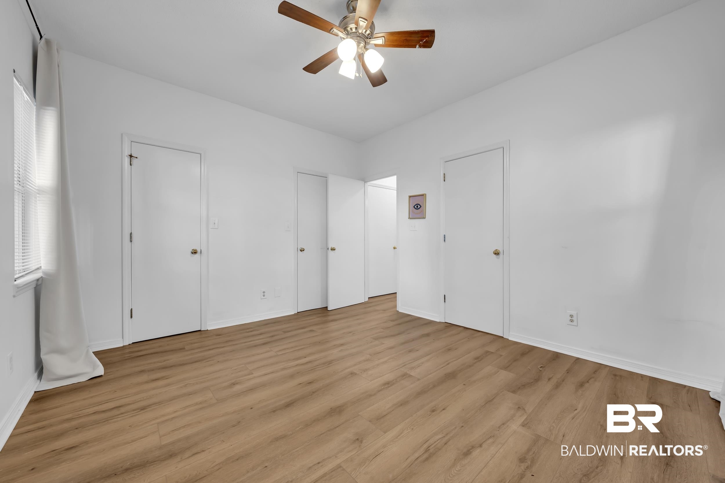 17488 Pandion Ridge, Unit A1 Fairhope, AL 36532 - Photo 11 of 18 Interior room featuring wood-finish flooring, white walls, and a ceiling fan with light fixture