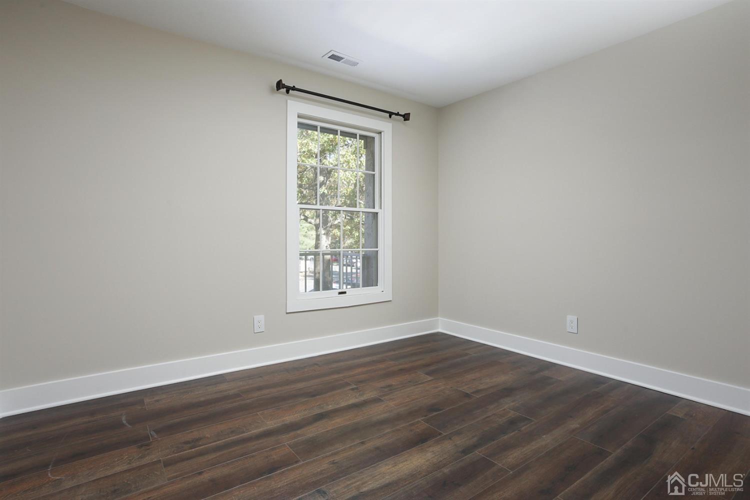 205 Commons Way Drive, Unit 5 East Brunswick, NJ 08816 - Photo 16 of 22 a view of an empty room with wooden floor and a window
