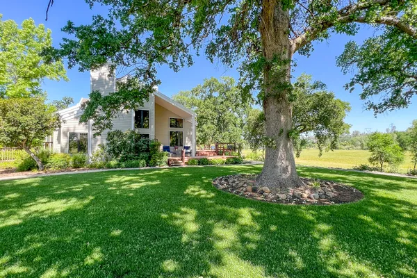 a view of a brick house with a big yard and large trees