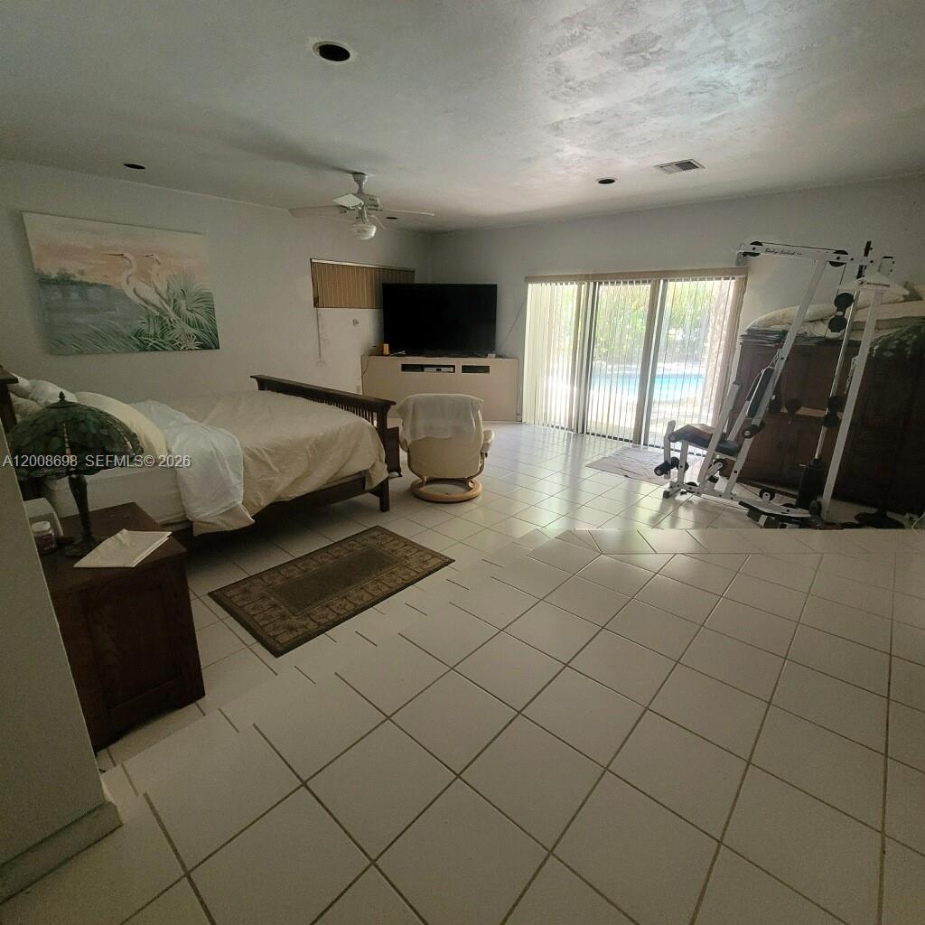8339 Southwest 112th Street Miami, FL 33156 - Photo 22 of 30 a bedroom with a bed a couch and a flat tv screen on the dresser